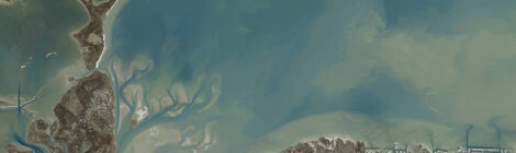 Aerial view of a coastal estuary with sandy shores and water channels.