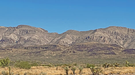 Scenic desert landscape with rugged mountains under a clear blue sky.