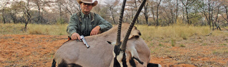 Hunter posing with a hunted oryx in a natural setting.