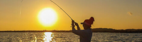 Wading angler casting at sunset